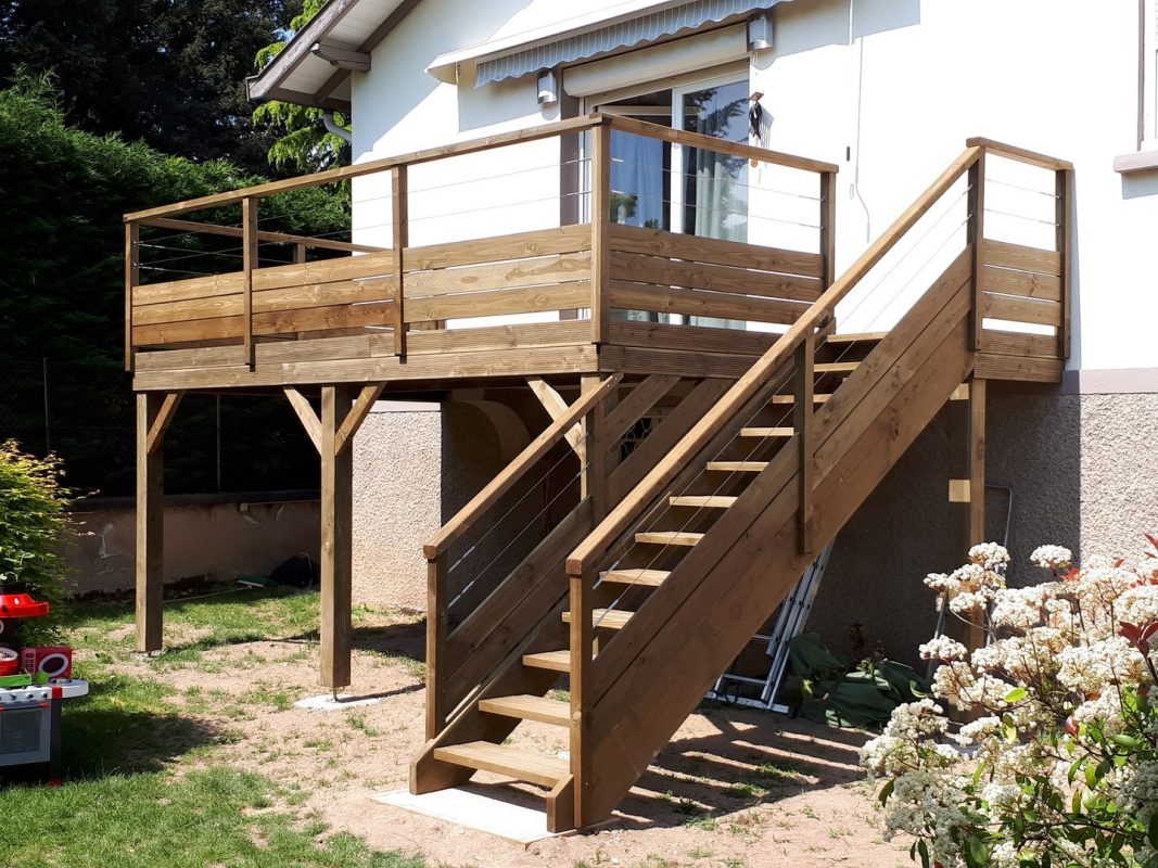 terrasse surélevée en bois avec escalier montant adossé à une maison blanche